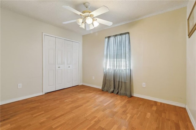 unfurnished bedroom with a textured ceiling, light wood finished floors, and baseboards