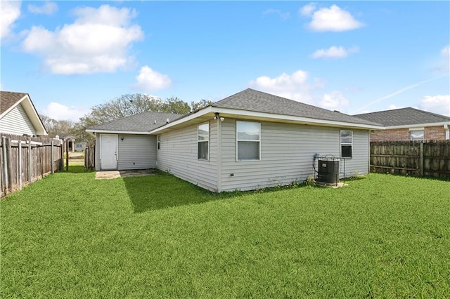 rear view of property featuring a yard, a fenced backyard, and central air condition unit