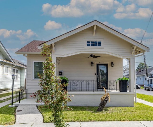 bungalow-style home featuring ceiling fan, a front lawn, a porch, and a shingled roof