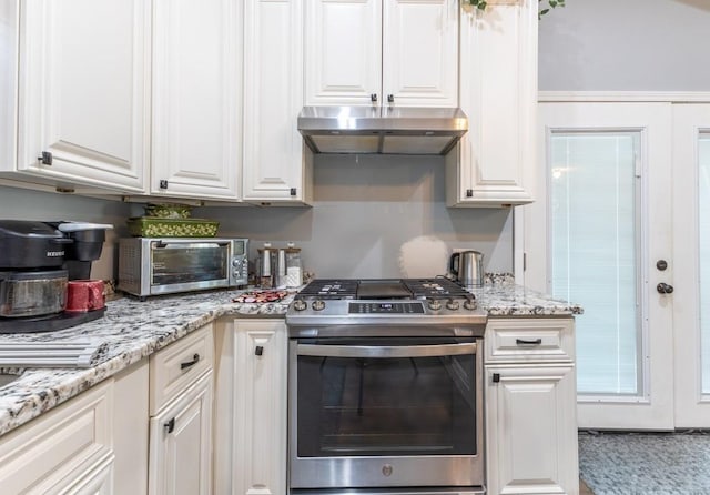 kitchen with under cabinet range hood, white cabinetry, and gas stove