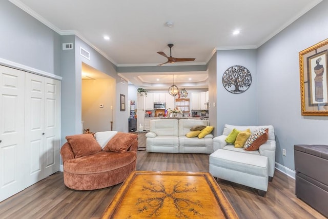 living area with recessed lighting, wood finished floors, visible vents, and crown molding