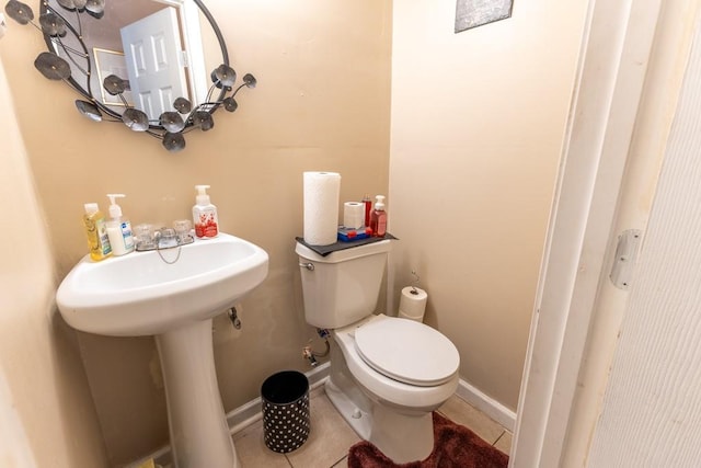 bathroom with toilet, tile patterned flooring, baseboards, and a sink