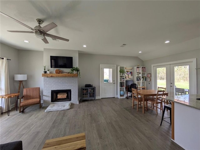 living room with a brick fireplace, dark wood-style floors, and a wealth of natural light