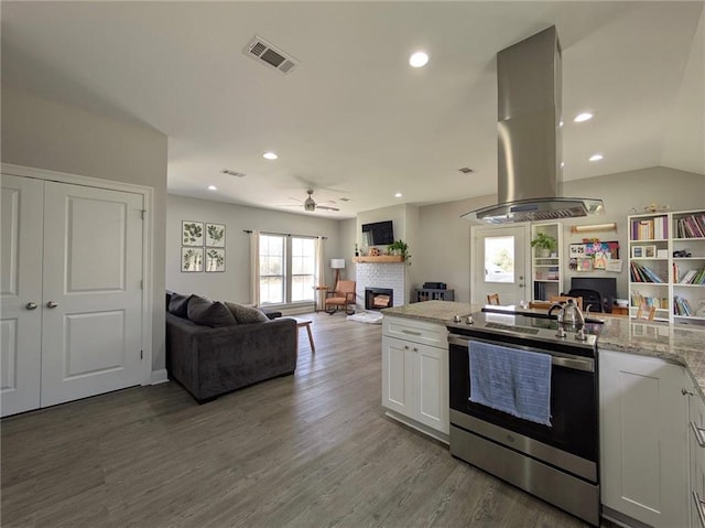 kitchen with island range hood, a fireplace, wood finished floors, stainless steel range with electric cooktop, and open floor plan