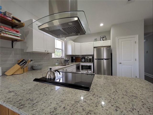 kitchen with island range hood, appliances with stainless steel finishes, tasteful backsplash, and light stone counters