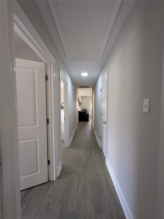 hall with baseboards, attic access, ornamental molding, and wood finished floors