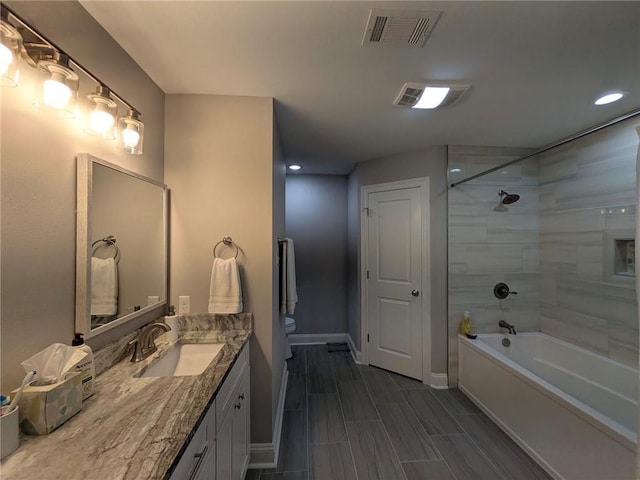 bathroom with toilet, vanity, visible vents, baseboards, and shower / washtub combination