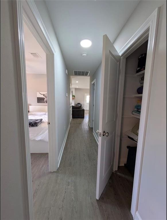 hall with visible vents, baseboards, and wood finished floors