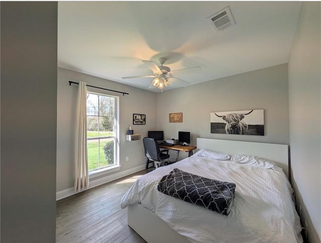 bedroom with ceiling fan, wood finished floors, visible vents, and baseboards