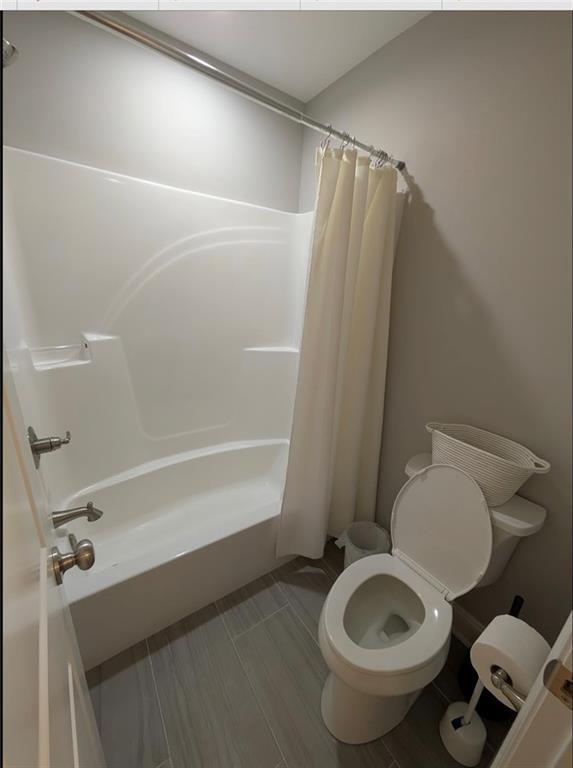 full bathroom with toilet and shower / bath combo with shower curtain