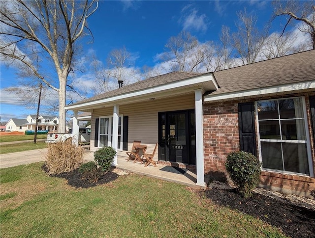 back of house featuring brick siding, a lawn, and a shingled roof