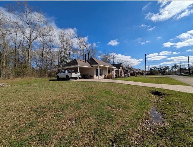 exterior space featuring concrete driveway and a lawn