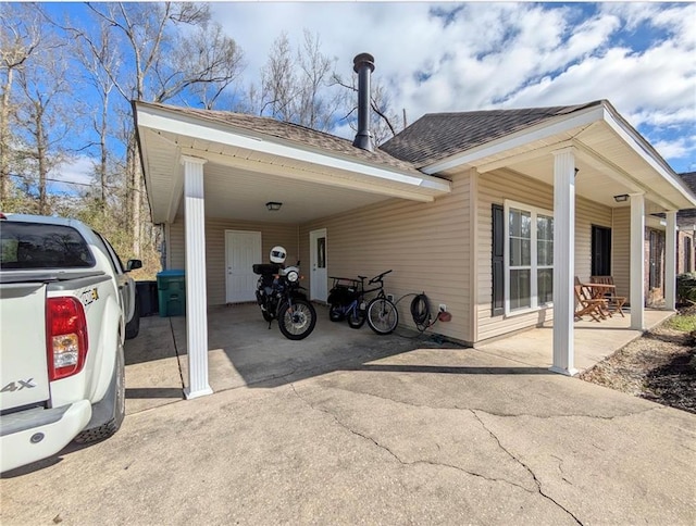 view of side of property featuring a shingled roof, an attached carport, and concrete driveway