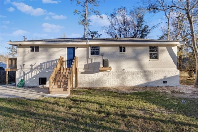 back of property with stairs, a yard, brick siding, and central AC unit