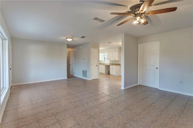 empty room featuring ceiling fan, a sink, visible vents, and baseboards