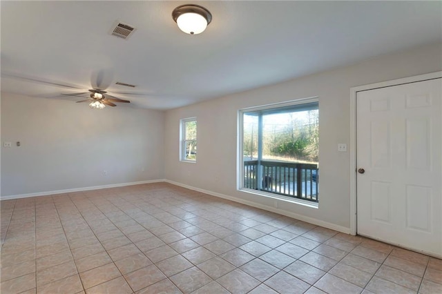 spare room featuring a ceiling fan, visible vents, baseboards, and light tile patterned floors