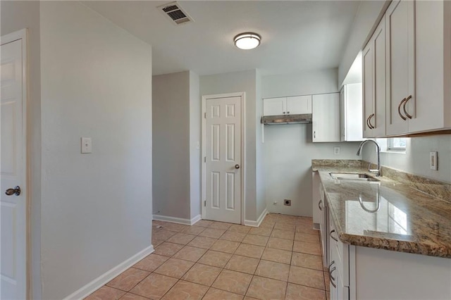 kitchen featuring light tile patterned floors, visible vents, white cabinetry, a sink, and light stone countertops