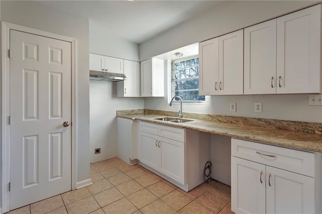 kitchen featuring light stone counters, white cabinets, and a sink