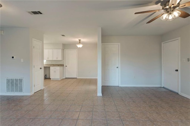 interior space with ceiling fan, visible vents, and baseboards