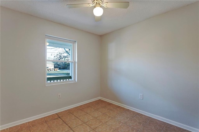 spare room with a ceiling fan, a textured ceiling, and baseboards