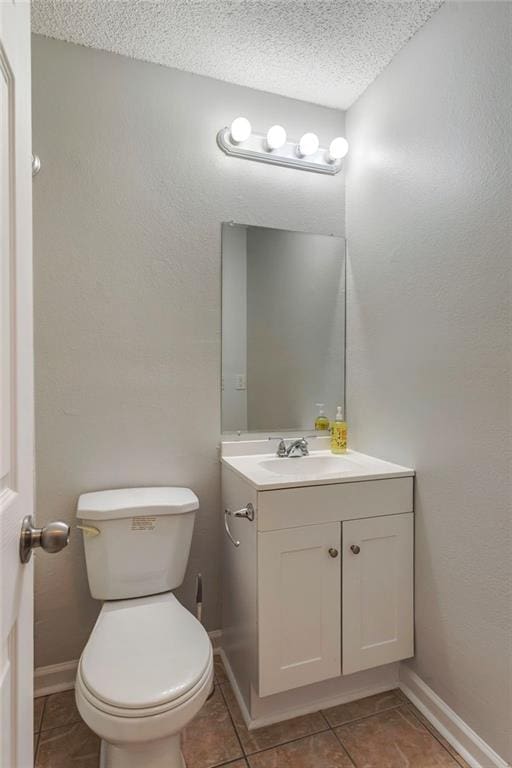 bathroom with a textured ceiling, vanity, toilet, and baseboards