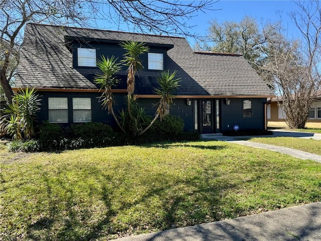 view of front of home featuring roof with shingles and a front yard