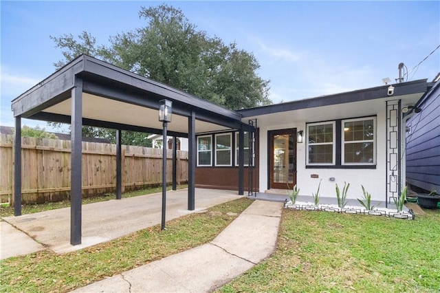 view of front of home featuring a carport, a front lawn, and fence