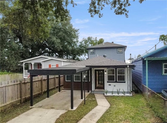 view of front facade with a front yard, fence, and roof with shingles