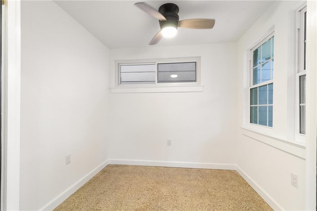 empty room featuring baseboards, light speckled floor, and ceiling fan