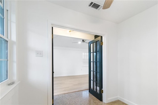 unfurnished room with speckled floor, a ceiling fan, visible vents, and baseboards