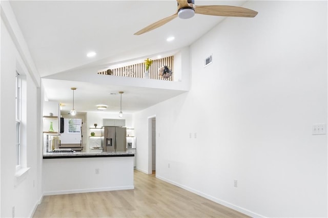 kitchen featuring a ceiling fan, visible vents, a peninsula, vaulted ceiling, and stainless steel fridge