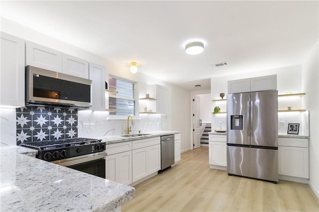 kitchen with open shelves, visible vents, appliances with stainless steel finishes, and a sink