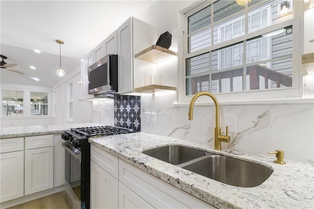 kitchen with black range with gas cooktop, stainless steel microwave, light stone countertops, and a sink