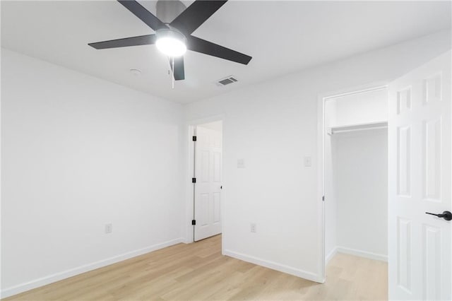 unfurnished bedroom with light wood-style flooring, a spacious closet, visible vents, and baseboards