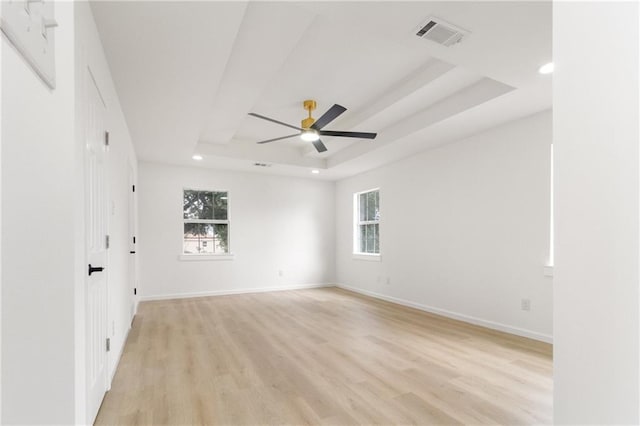 unfurnished room with visible vents, baseboards, a raised ceiling, and light wood-style floors