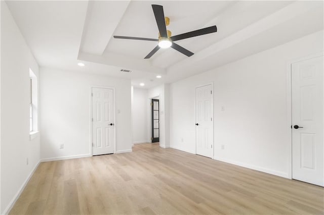 unfurnished bedroom featuring visible vents, baseboards, light wood finished floors, recessed lighting, and a raised ceiling