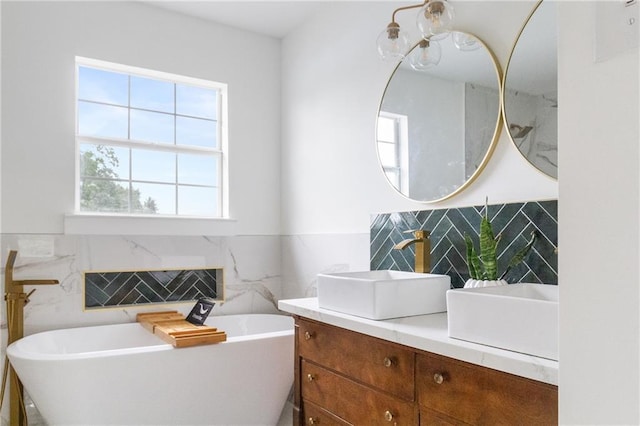 full bathroom with vanity, tile walls, a freestanding tub, and wainscoting