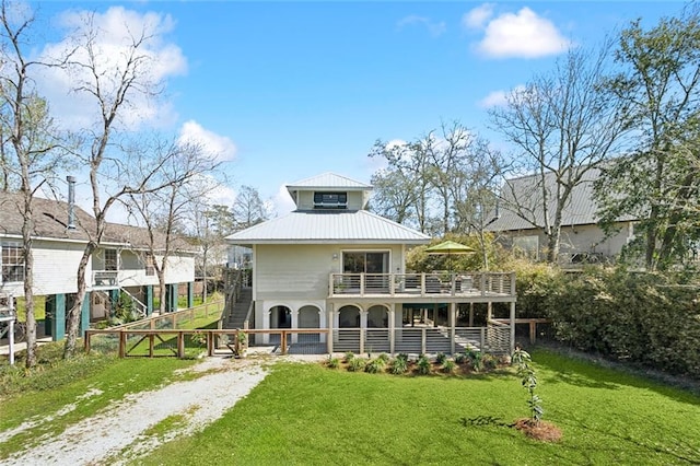 rear view of property with metal roof, driveway, a yard, and stairway