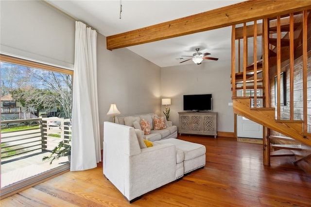 living area with ceiling fan, beamed ceiling, and wood finished floors