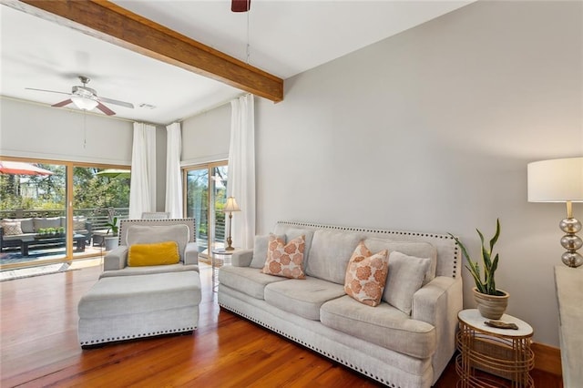 living area featuring beamed ceiling, wood finished floors, and a ceiling fan