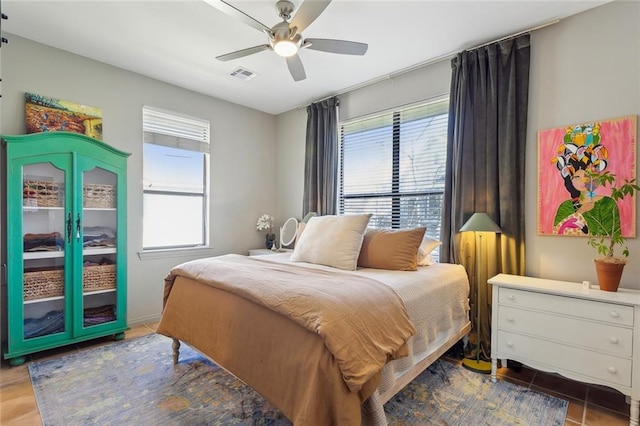 tiled bedroom with visible vents, ceiling fan, and multiple windows