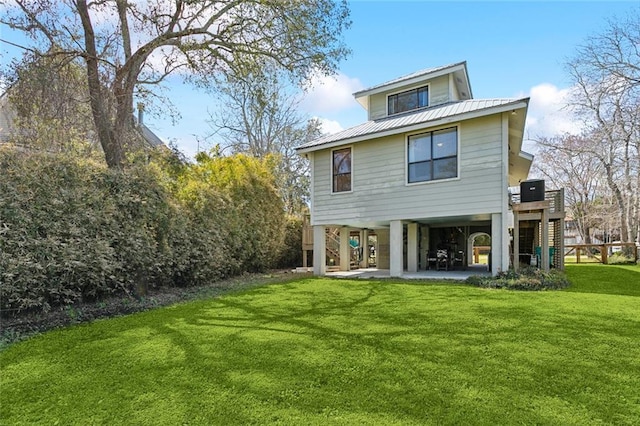 rear view of property with metal roof, a patio, stairway, a lawn, and a carport