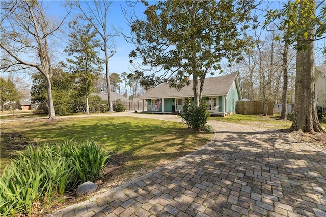 view of front facade featuring decorative driveway, a front yard, and fence