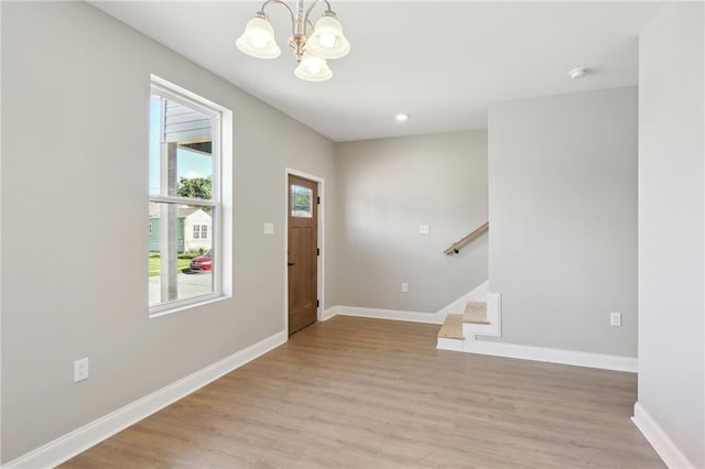 foyer entrance featuring baseboards, a notable chandelier, light wood-style flooring, and stairs