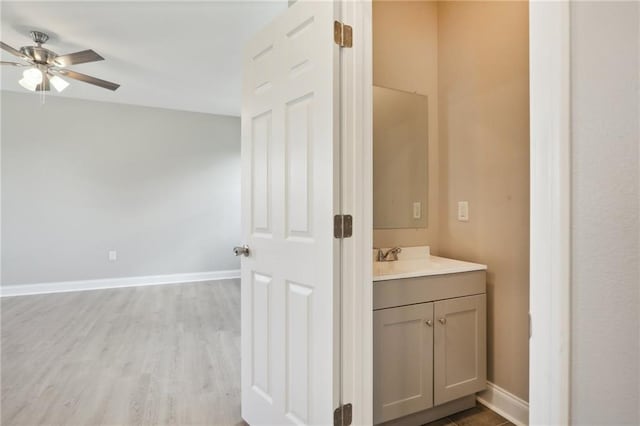 bathroom featuring vanity, wood finished floors, baseboards, and ceiling fan