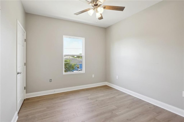 spare room with baseboards, light wood finished floors, and ceiling fan