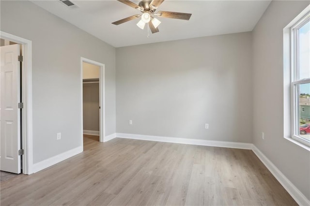 spare room featuring ceiling fan, light wood-style floors, visible vents, and baseboards