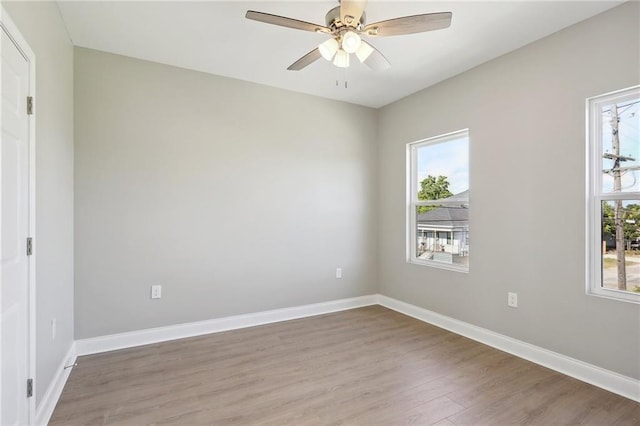 spare room with light wood-style flooring, a ceiling fan, and baseboards