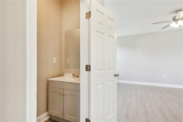 bathroom featuring vanity, wood finished floors, baseboards, and ceiling fan