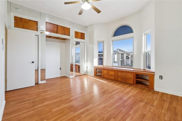 interior space with baseboards, ceiling fan, light wood finished floors, and multiple closets